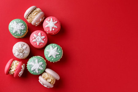 Beautifully decorated Christmas macarons on red background, flat lay. Space for textの写真素材