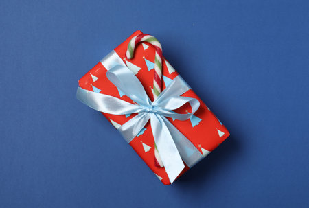 Decorated Christmas gift with candy cane on blue background, top viewの写真素材