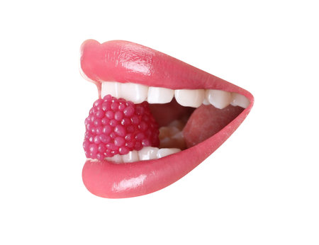 Woman with beautiful color lips holding raspberry candy in her mouth on white background, closeup