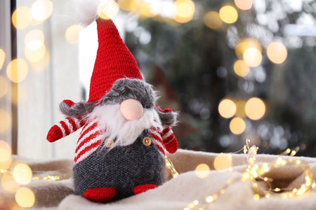 Christmas gnome on blanket near window at home, space for text. Bokeh effectの写真素材