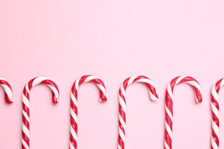 Merry Christmas and Happy New Year. Tasty candy canes on pink background, flat lay. Space for textの写真素材