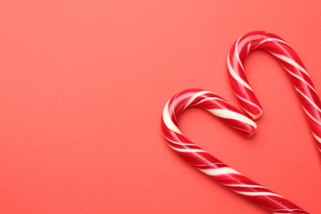 Heart made of tasty candy canes on red background, flat lay with space for text. Merry Christmas and Happy New Yearの写真素材