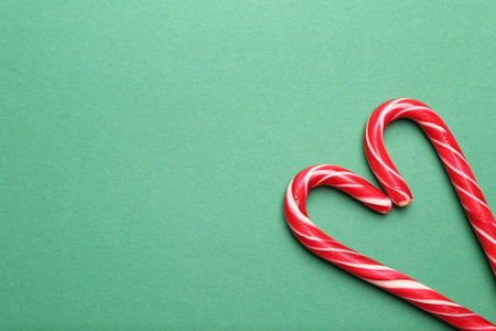 Heart made of candy canes on green background, top view with space for text. Merry Christmas and Happy New Yearの写真素材
