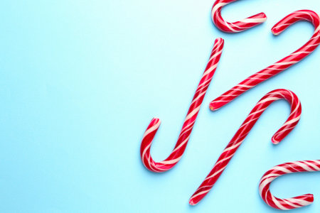 Tasty candy canes on light blue background, flat lay with space for text. Merry Christmas and Happy New Yearの写真素材