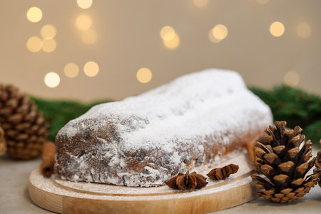 Traditional Christmas Stollen with icing sugar, spices and festive decor on gray table, closeup. Bokeh effectの写真素材