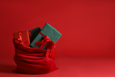 Santa Claus bag with Christmas gifts on red background. Space for textの写真素材