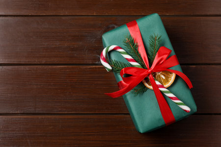 Decorated Christmas gift with candy cane on wooden background, top view. Space for textの写真素材