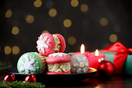 Tasty macarons and Christmas decor on black wooden table against blurred lights, closeup. Space for textの写真素材