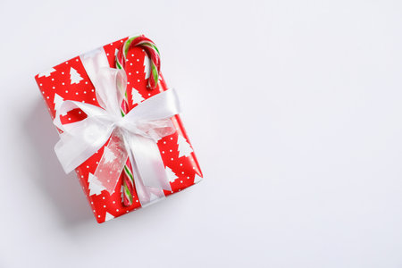 Decorated Christmas gift with candy cane on white background, top view. Space for textの写真素材
