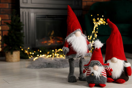 Funny Christmas gnomes on floor in decorated room, space for textの写真素材