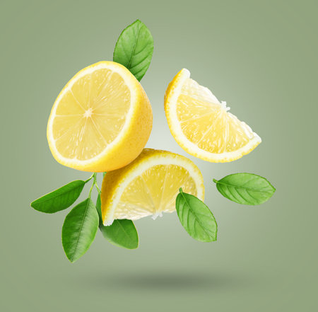 Fresh lemons and green leaves flying in air on gray backgroundの写真素材