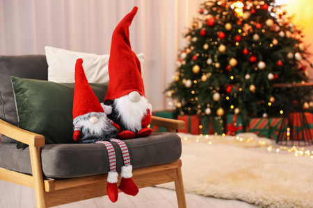 Funny Christmas gnomes on armchair in decorated room, space for textの写真素材