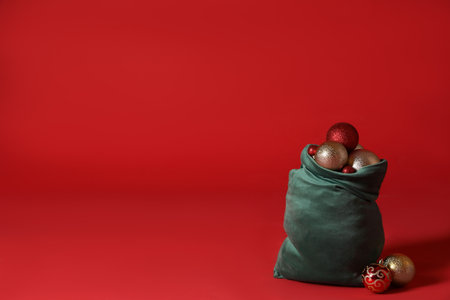 Santa Claus bag with baubles on red background, space for text. Merry Christmasの写真素材