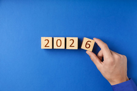 Man putting cube with number 6 on blue background, top view