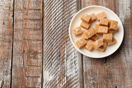 Tasty caramel candies with salt on color wooden table, top view. Space for textの写真素材