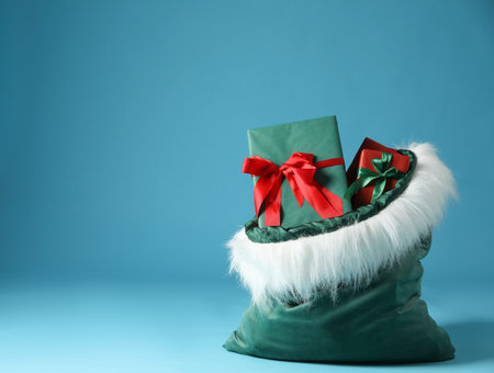 Santa Claus bag with Christmas gifts on light blue background, closeup. Space for textの写真素材