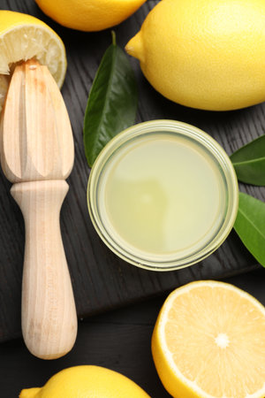 Fresh lemon juice, fruits and squeezer on black wooden table, flat layの写真素材