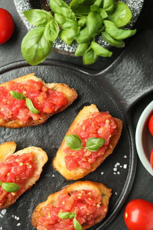 Tasty bruschettas with tomatoes and basil served on black table, flat layの写真素材