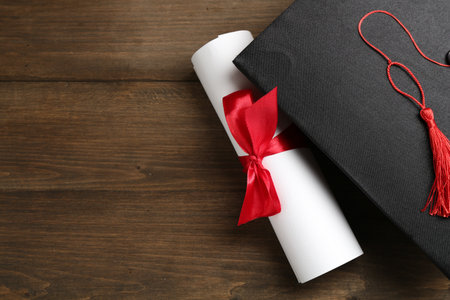 Graduation cap and diploma on wooden table, top view. Space for textの写真素材