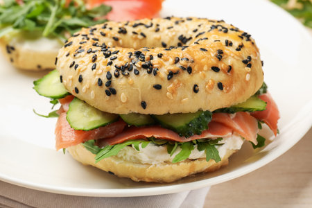 Bagel with salmon, cream cheese, cucumber and arugula on table, closeupの写真素材