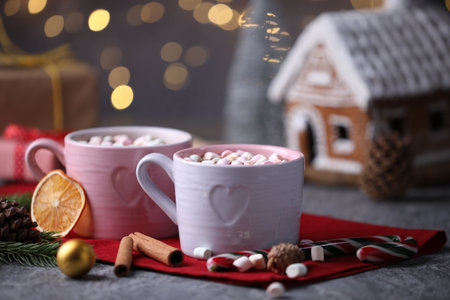Tasty cocoa with marshmallows, cinnamon and Christmas decor on gray table against blurred lights, closeupの写真素材