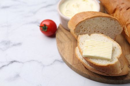 Slices of baguette with butter and tomato on white marble table, closeup. Space for textの写真素材