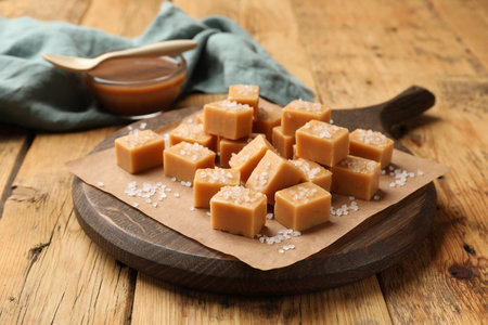 Tasty candies with salt and caramel sauce on wooden table, closeupの写真素材