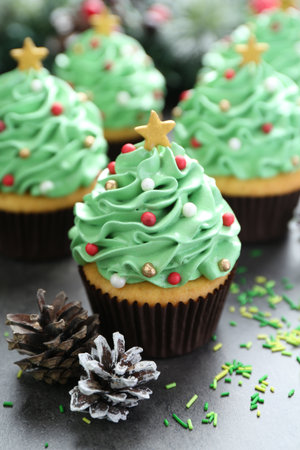 Christmas tree shaped cupcakes and festive decor on gray table, closeup