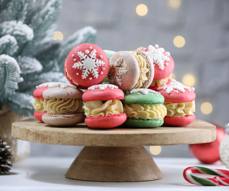 Tasty Christmas macarons on wooden stand against blurred lights, closeupの写真素材