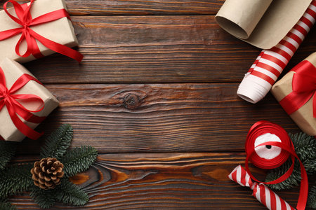 Festive packaging. Gift boxes, ribbon, wrapping paper and Christmas decor on wooden table, flat lay. Space for textの写真素材