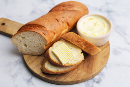 Cut baguette with butter on white marble table, closeupの写真素材