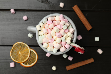 Tasty hot cocoa with marshmallows, candy cane, cinnamon and dried orange slices on wooden table, flat layの写真素材
