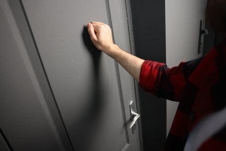 Man knocking on apartment door, closeup view
