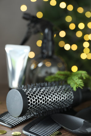 Different hairdresser's tools and Christmas tree branches on wooden table against background with blurred lights, closeupの写真素材