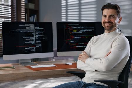 Portrait of smiling programmer with crossed arms on chair at workplaceの写真素材