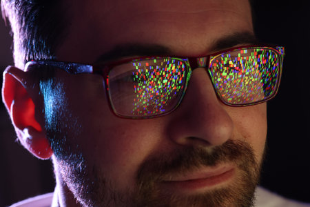 Man wearing glasses with reflection on black background in color light, closeupの写真素材
