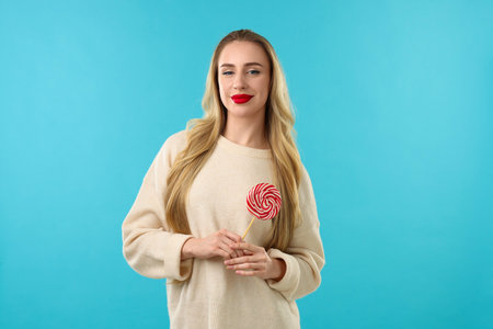 Christmas celebration. Woman with lollipop on light blue backgroundの写真素材