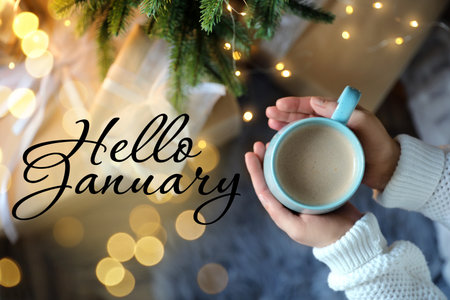 Hello January card. Woman holding hot drink near Christmas treeの写真素材