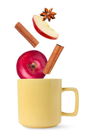 Health boosting drink for cold season. Apples, cinnamon and anise falling into cup on white backgroundの写真素材