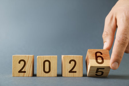 Man flipping cube with numbers 5 and 6 to make 2026 on gray background, closeup