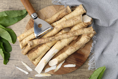 Fresh raw horseradish roots, peeler and leaves on wooden table, flat layの写真素材