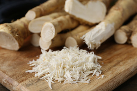 Grated horseradish and fresh roots on wooden table, closeupの写真素材