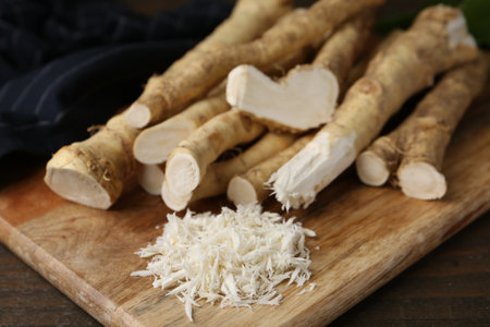 Grated horseradish and fresh roots on wooden table, closeupの写真素材