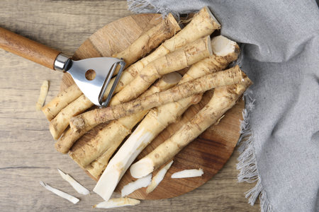 Fresh raw horseradish roots and peeler on wooden table, top viewの写真素材