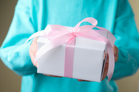 Woman with gift box on beige background, closeupの写真素材
