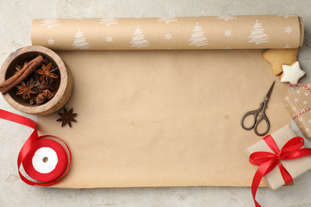 Festive packaging. Wrapping paper, gingerbread cookies, spices, scissors and gift boxes on light textured table, flat lay with space for text.の写真素材