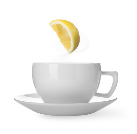 Citrus drink for health boosting. Lemon piece falling into cup on white background. Cold season remedyの写真素材