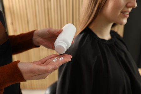 Hairstylist with talcum powder and her client at salon, closeupの写真素材