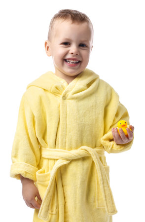 Smiling little boy in yellow bathrobe with rubber duck on white backgroundの写真素材