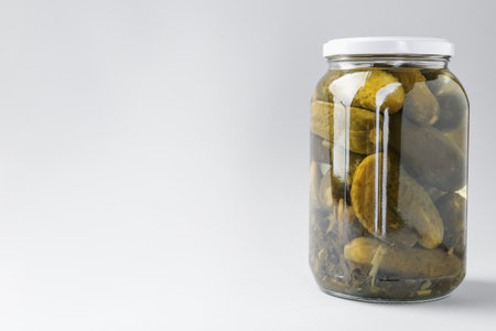 Pickled cucumbers in jar on light background. Space for textの写真素材